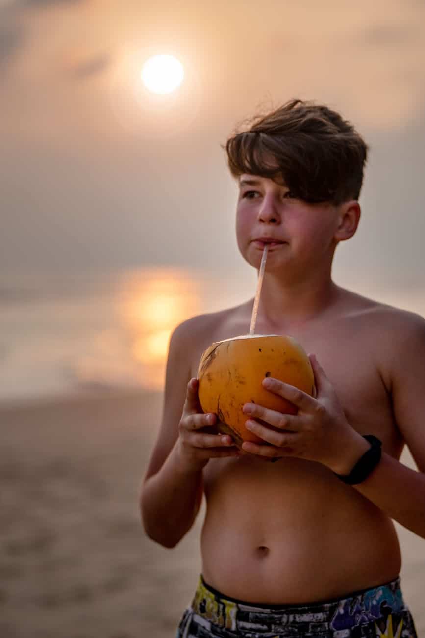 shirtless kid drinking a coconut juice